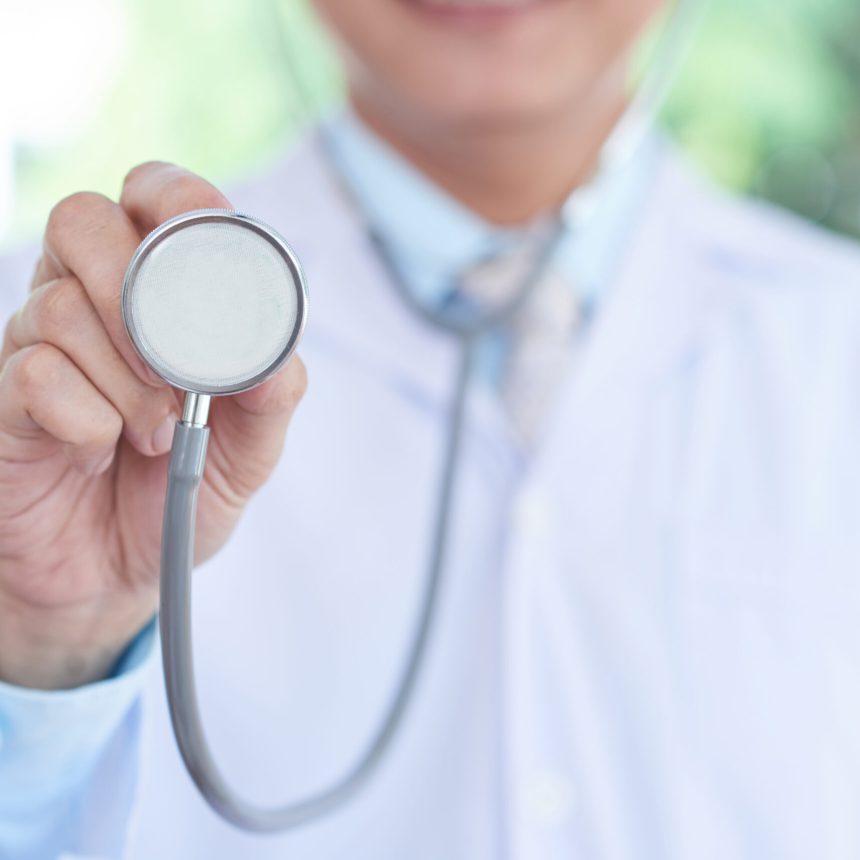 Close-up of medical specialist holding stethoscope and listening to heartbeat