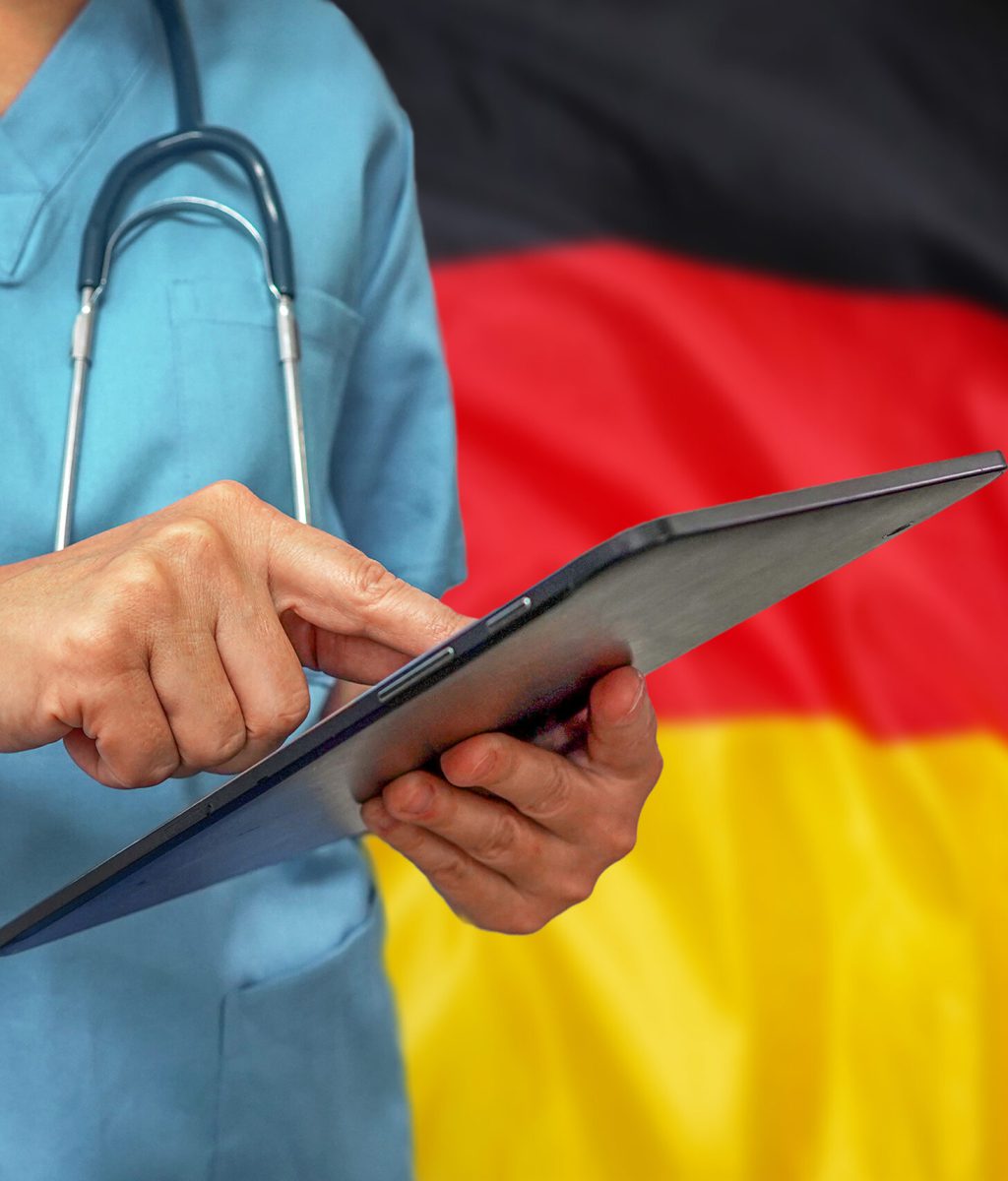 Surgeon or doctor using a digital tablet on the background of the Germany flag. Medical equipment or medical network, technology and diagnostics in Germany.